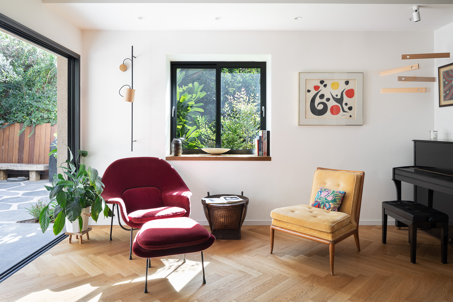 A completed living space with vintage seating, art and garden views