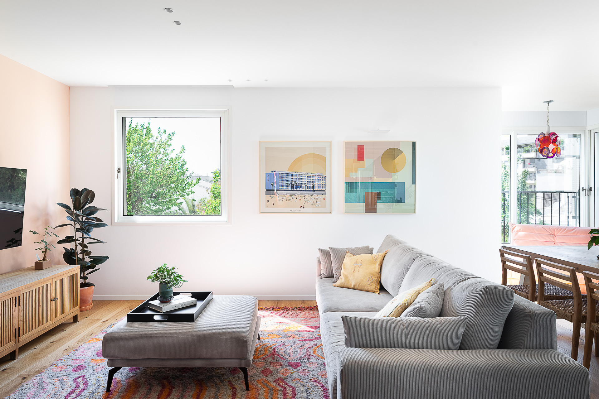 A light-filled living and dining space with colourful artwork
