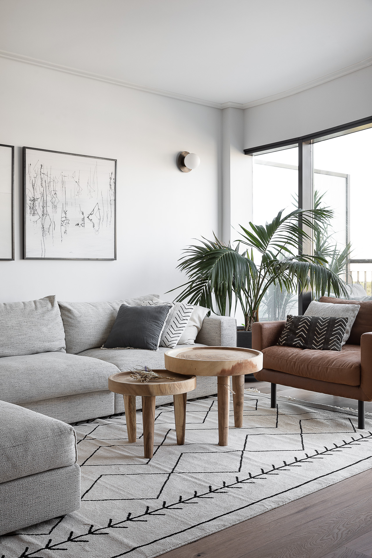 A neutral living room with layered seating and indoor palms